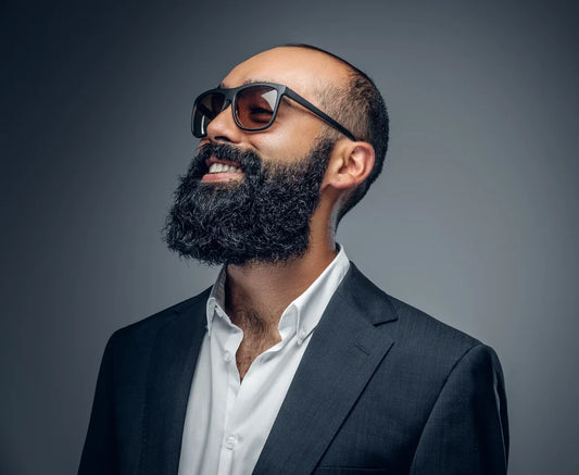 Homem de terno e óculos escuros com barba cheia densa e bem alinhada, exemplo de tipo de barba masculina